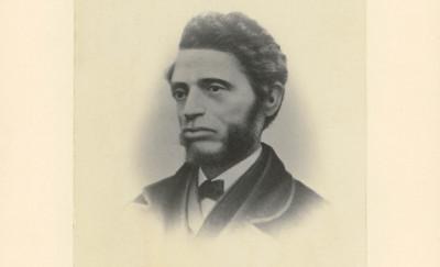 black-and-white profile photograph of a man with a bear waring a jacket and tie. photo is labeled 'William C Nell' in pencil.